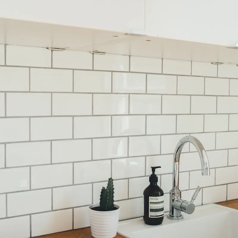 Close-up of a matte black tap against a handmade tile backsplash
