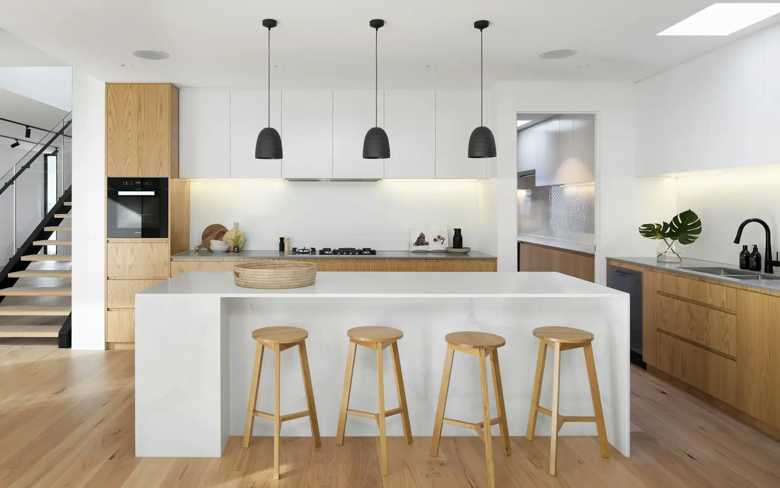 Modern two-tone kitchen island with oak bar stools in a Toronto home